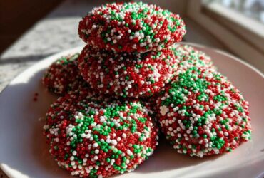 A stack of rich, round christmas sprinkle cookies covered entirely in red, green, and white nonpareils.