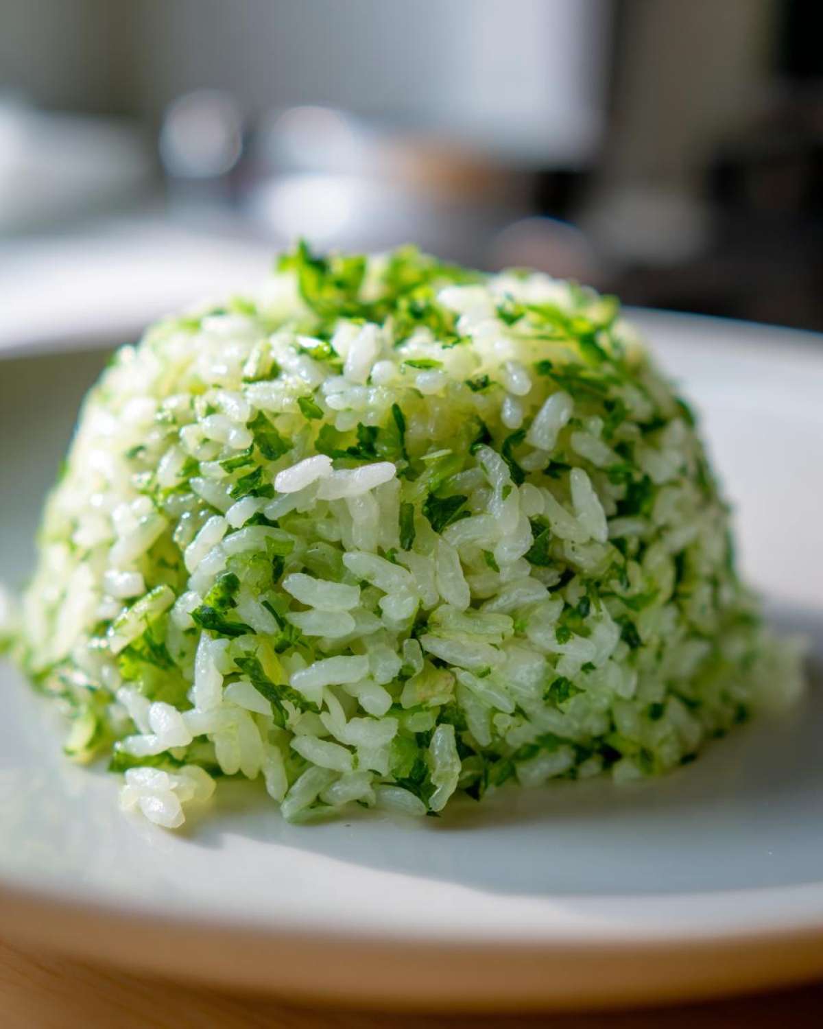 A perfectly molded mound of bright green cilantro lime rice served on a white plate.