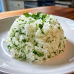 A perfectly molded serving of fluffy cilantro lime rice garnished with fresh chopped cilantro.