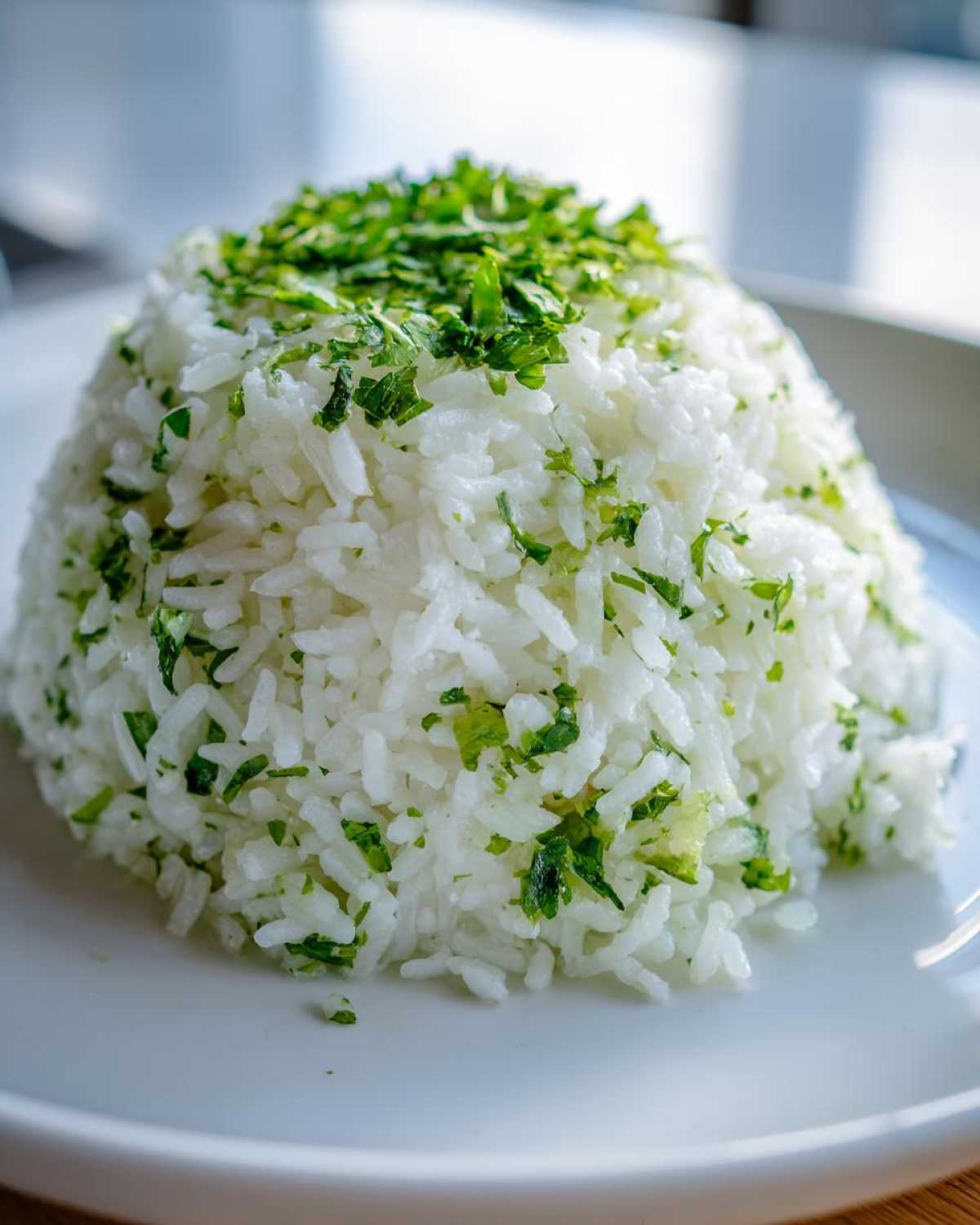 A close-up of a perfectly molded mound of white cilantro lime rice topped with fresh chopped cilantro.
