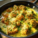 Close-up of tender pieces of coconut lime chicken simmering in a rich, yellow, creamy sauce and garnished with fresh cilantro.