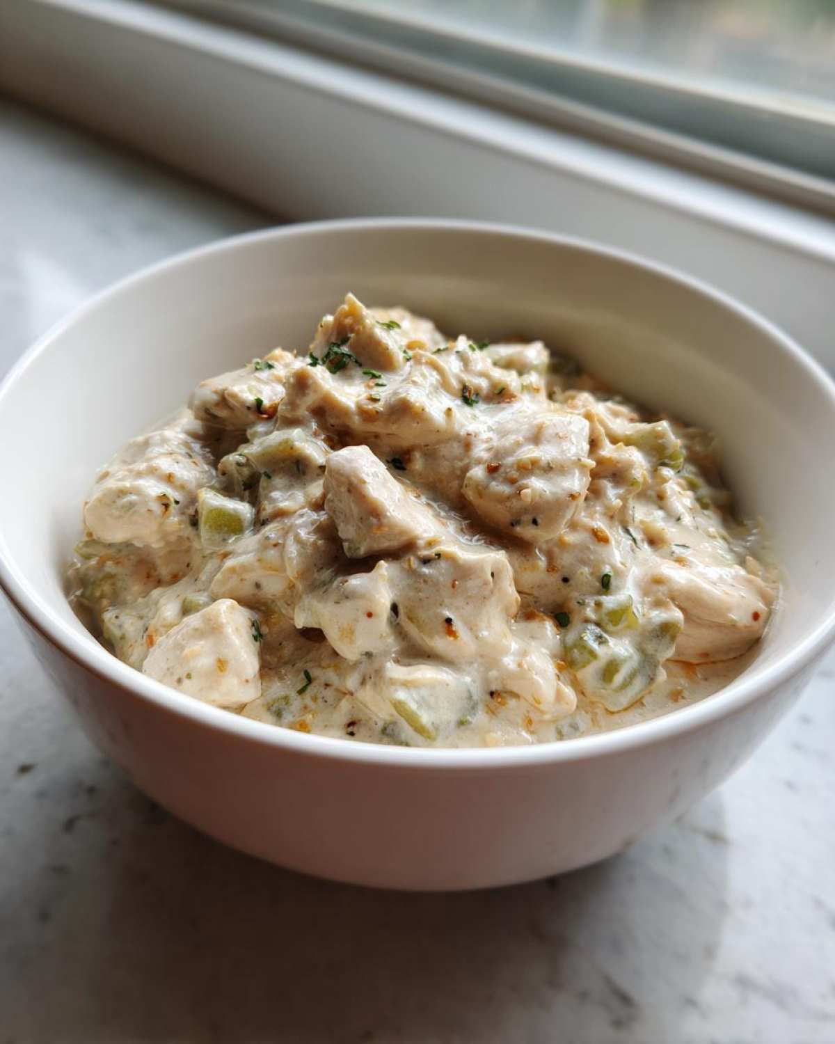 Close-up of creamy crockpot white chicken chili featuring chunks of chicken and green peppers in a rich sauce.