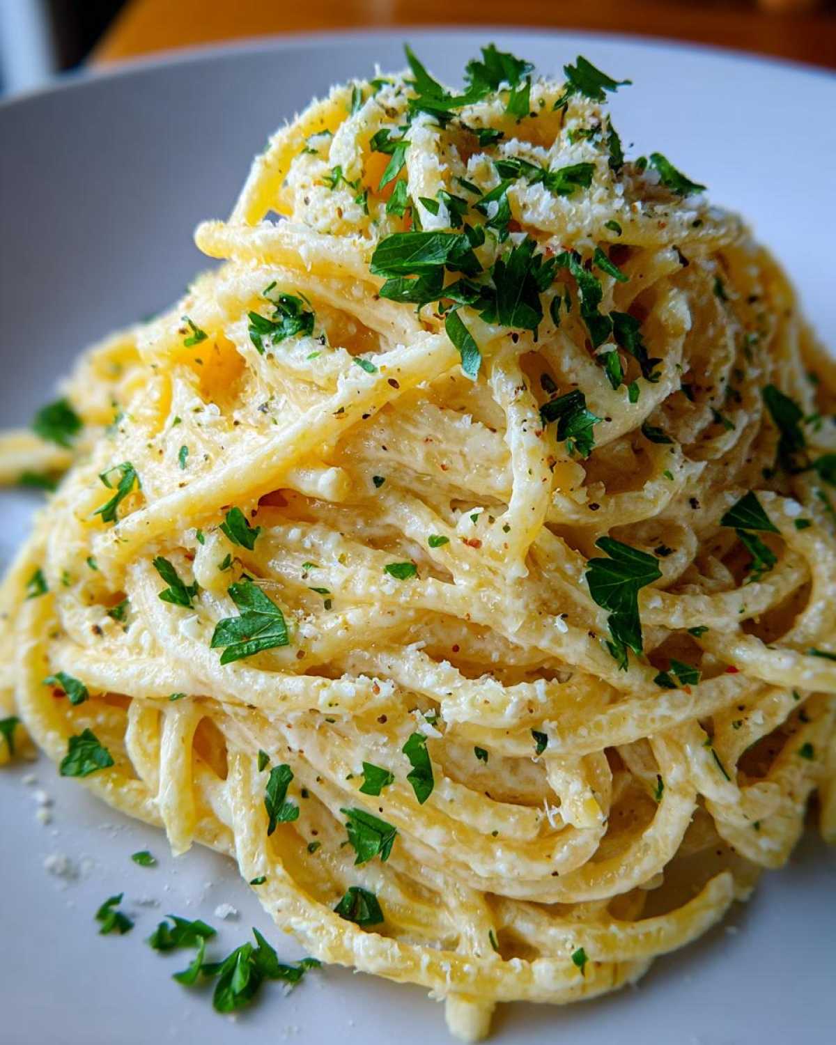 Close-up of creamy spaghetti tossed in a rich garlic parmesan sauce, topped with fresh parsley.