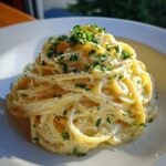 Close-up of creamy pasta coated in a rich sauce, garnished with fresh parsley, likely a garlic parmesan recipe.
