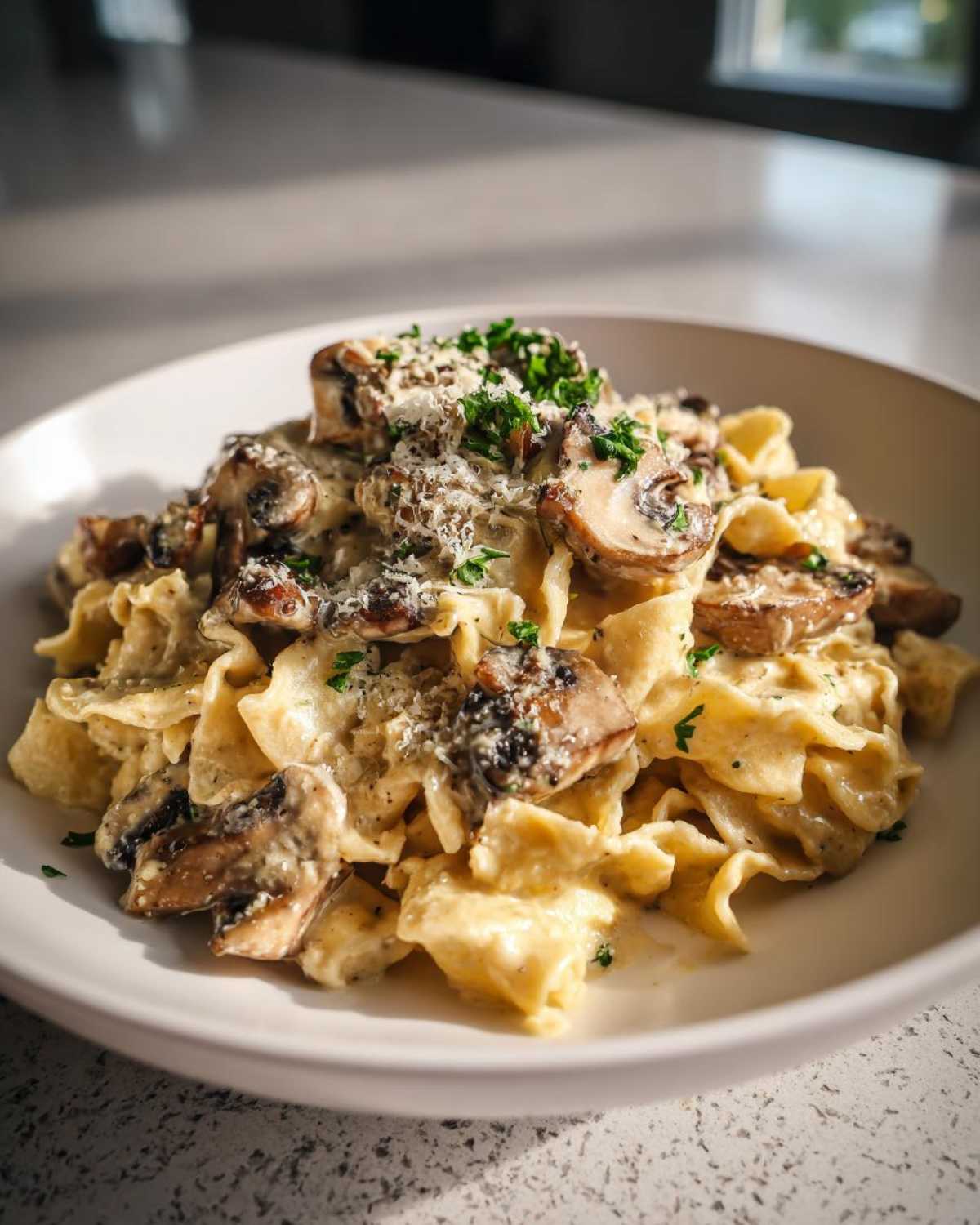 A close-up of creamy mushroom pasta topped with grated Parmesan cheese and fresh parsley.