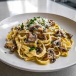 A close-up of creamy fettuccine mushroom pasta topped with grated Parmesan cheese and fresh parsley.