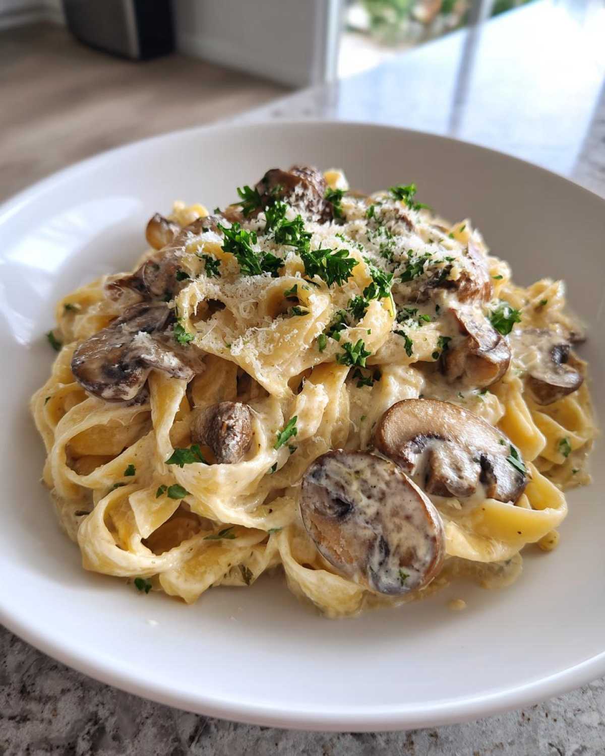 A close-up of creamy fettuccine mushroom pasta topped with grated Parmesan and fresh parsley.