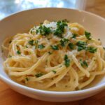 Close-up of creamy spaghetti tossed in a rich sauce, topped with grated parmesan pasta and fresh parsley.