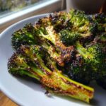 Close-up of perfectly roasted broccoli with dark, crispy edges and bright green stems.
