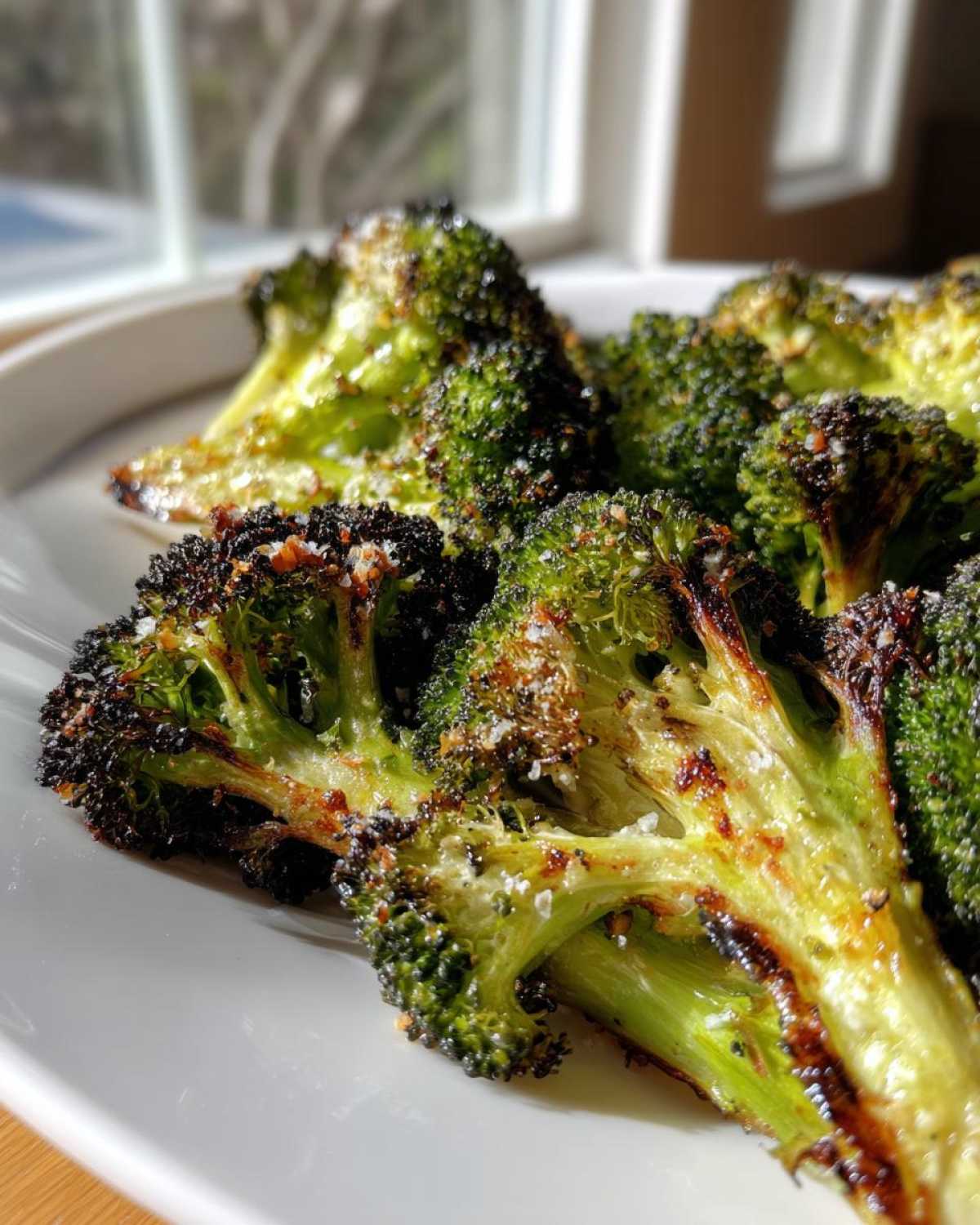 Close-up of perfectly roasted broccoli with charred edges and visible salt crystals, highlighting crisp texture.