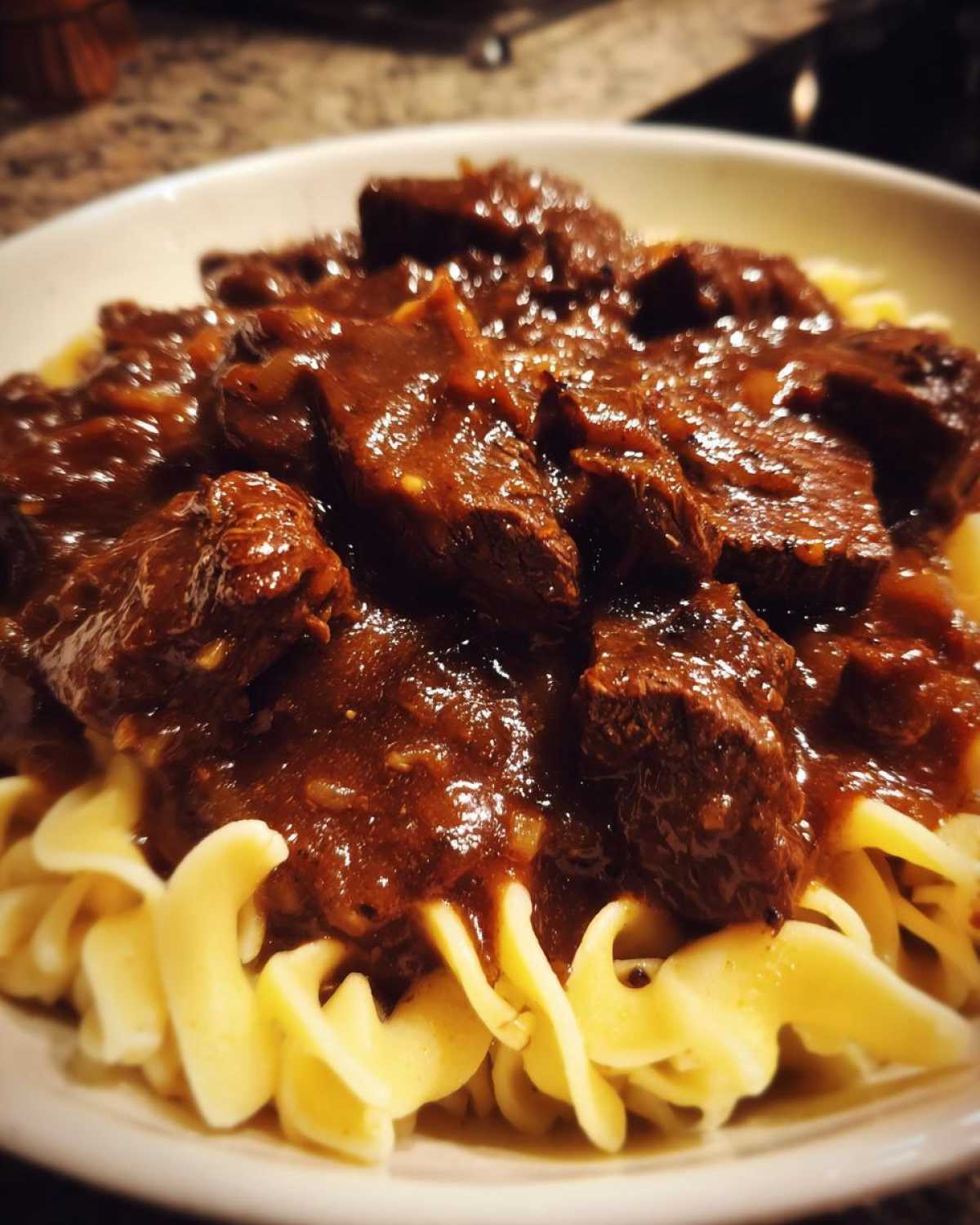 Close-up of tender crockpot beef tips smothered in rich brown gravy served over egg noodles.