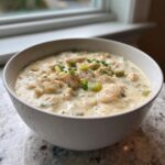 A close-up of a hearty bowl of creamy crockpot white chicken chili, topped with green onions.
