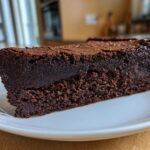 Close-up of a dense, fudgy slice of flourless chocolate cake served on a white plate.