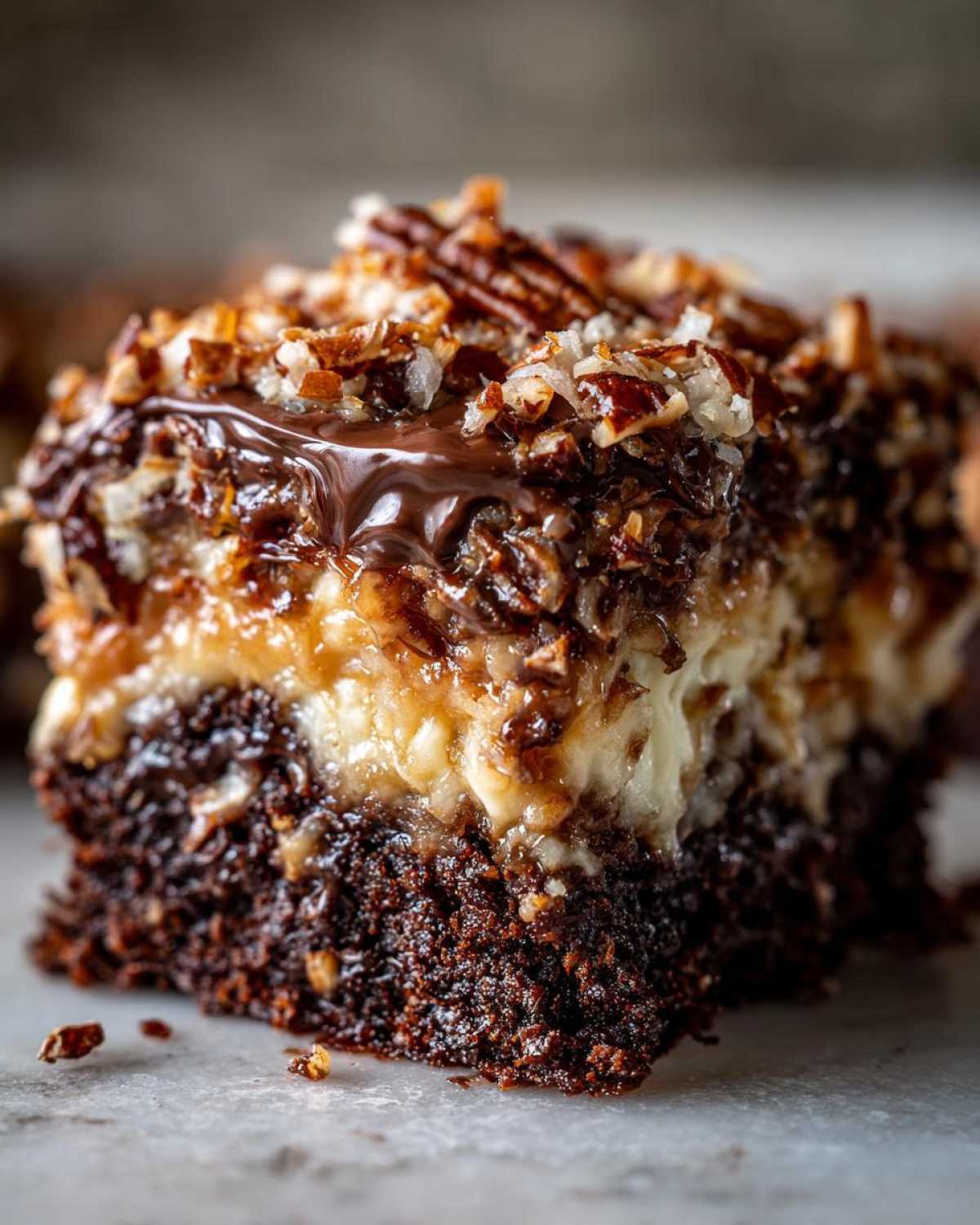 Close-up of a rich, moist slice of german chocolate poke cake showing the chocolate base and coconut-pecan topping.