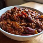 Close-up of a white bowl filled with rich, hearty chili featuring ground meat and kidney beans.