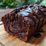 Close-up of a rich, dark chocolate hot fudge brownie bread loaf drizzled with glossy hot fudge sauce.