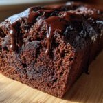 Close-up of a freshly baked hot fudge brownie bread loaf with rich chocolate glaze dripping down the side.