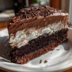 A rich slice of layered Italian love cake featuring a dark chocolate base, white cream layer, and chocolate mousse topping with shavings.