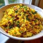 Close-up of vibrant yellow mediterranean rice topped with toasted pine nuts and fresh parsley.