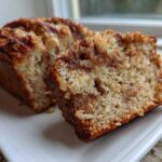 Close-up of a moist slice of apple bread showing cinnamon swirl and chopped nuts.