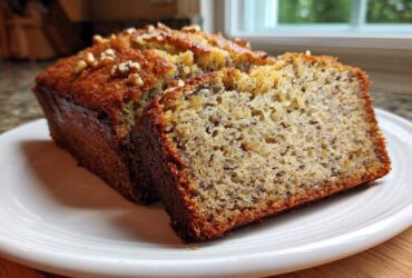 A close-up of a moist slice of greek yogurt banana bread, showing the crumb texture and walnut topping.