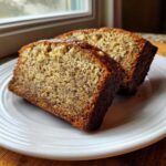 Two thick slices of moist greek yogurt banana bread showing a tender crumb with visible banana flecks.