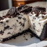 A generous slice of creamy Oreo pie with a dark chocolate crust, topped with whipped cream and whole Oreos.