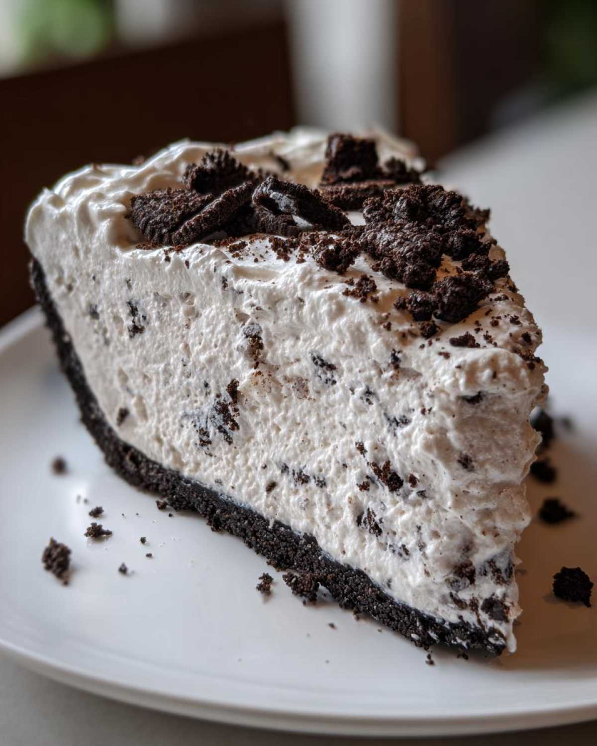 A generous slice of creamy, no-bake Oreo pie featuring a dark crust and white filling studded with cookie pieces.