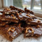 A pile of broken pieces of homemade peanut butter pretzel bark topped with sea salt.
