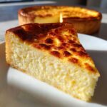 A thick slice of baked egg custard with a beautifully browned, slightly blistered top, sitting on a white plate.
