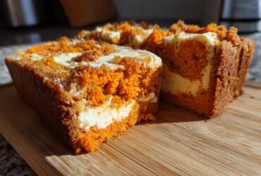 Close-up of two slices of moist pumpkin cream cheese bread with a visible cream cheese swirl and crumb topping.