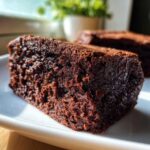 Close-up of a dense, rich slice of flourless chocolate cake served on a white plate.