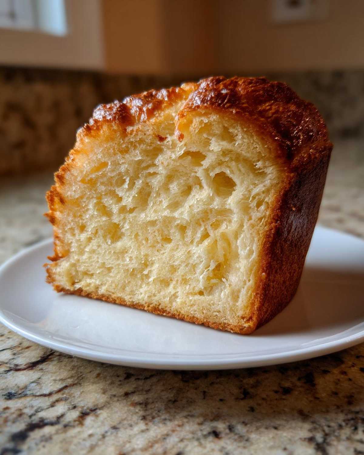 Close-up of a thick slice of golden brown beer bread showing its soft, airy interior texture.