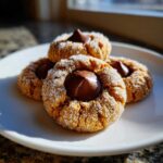 Three delicious peanut butter blossom cookies coated in sugar, featuring a chocolate kiss center.
