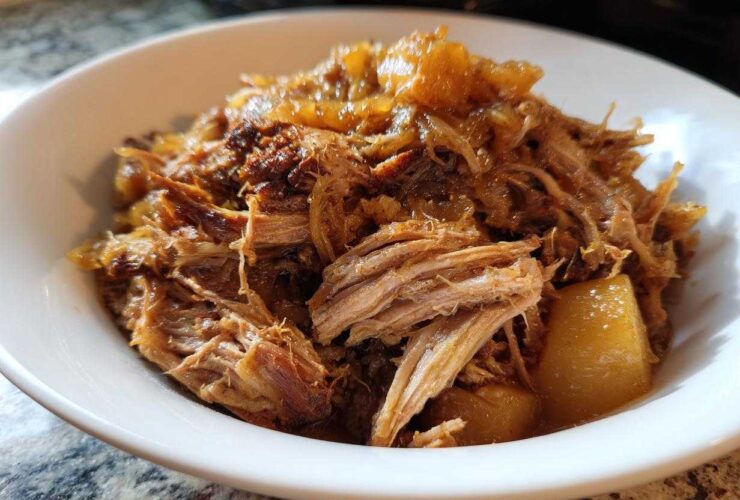 Close-up of tender, shredded pork and sauerkraut mixture served in a white bowl.