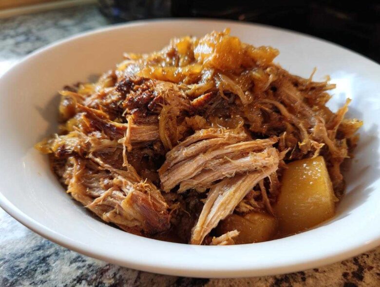 Close-up of tender, shredded pork and sauerkraut mixture served in a white bowl.