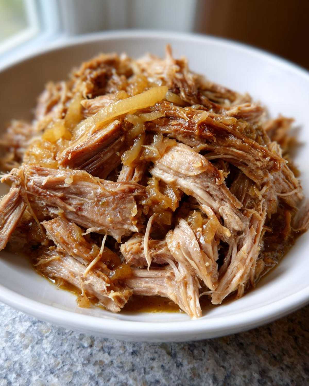 Close-up of tender, shredded pork and sauerkraut mixture served in a white bowl.