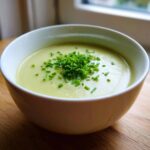 Close-up of a creamy bowl of leek soup garnished generously with fresh, chopped chives.
