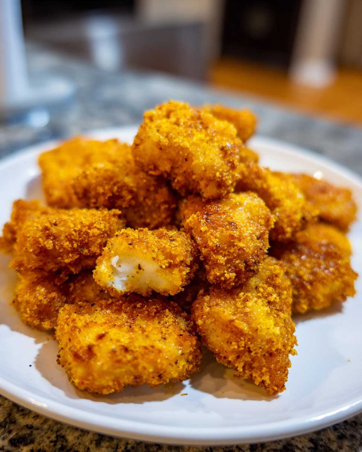A pile of golden brown Air Fryer Crispy Fish Nuggets with a visible flaky white interior on one nugget.