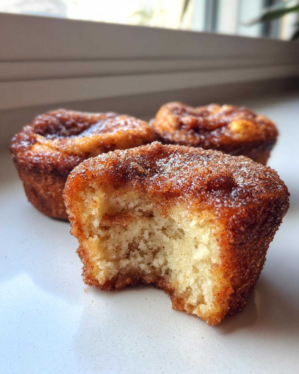 Close-up of a cinnamon sugar french toast muffin with a bite taken out, showing the fluffy interior.