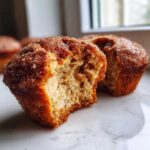 A cinnamon sugar french toast muffin broken in half showing the fluffy interior and sugary coating.