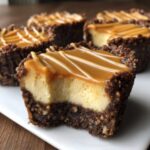 Close-up of a cookie butter cheesecake cup with a bite taken out, showing the creamy filling and dark crust, topped with caramel.