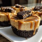 Close-up of individual cookie butter cheesecake cups topped with caramel drizzle and cookie crumbs.