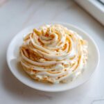 A beautiful swirl of Copycat Texas Roadhouse Cinnamon Honey Butter piped onto a small white plate.