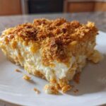 A close-up of a creamy slice of potato casserole with a crunchy, golden brown topping on a white plate.
