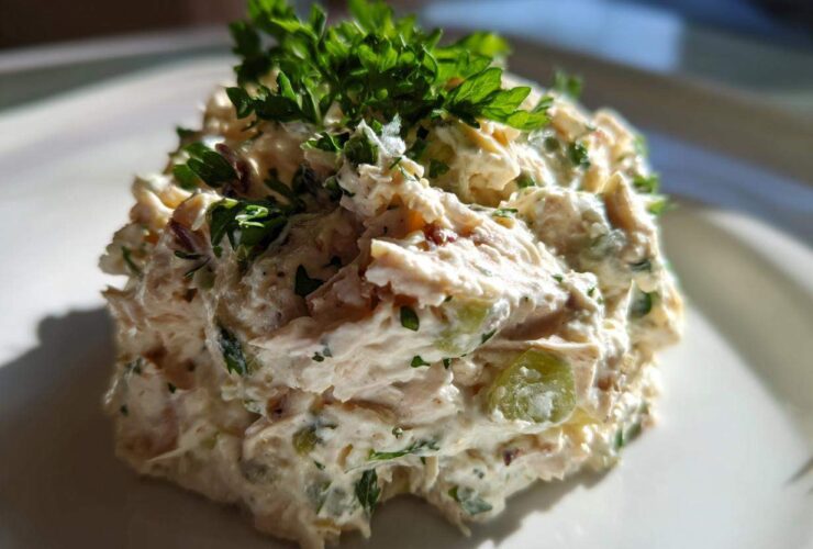 A close-up of a scoop of creamy greek yogurt chicken salad, garnished generously with fresh parsley.