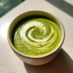 Close-up of vibrant green Instant Pot Creamy Asparagus Soup topped with a white cream swirl.