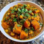 Close-up of Instant Pot Moroccan Chickpea Stew with sweet potatoes and chickpeas, topped with fresh cilantro.