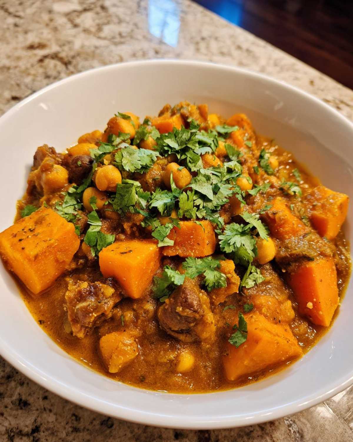A bowl of rich, savory Instant Pot Moroccan Chickpea Stew with sweet potatoes and fresh cilantro garnish.