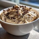 A white bowl filled with creamy Keto Chocolate Chip Cookie Dough Dip topped with chocolate chunks.